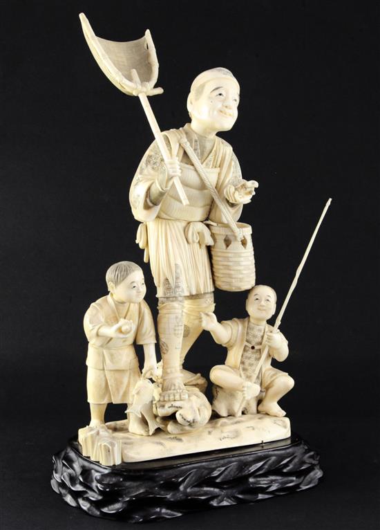 A large Japanese sectional walrus ivory okimono of a fisherman and two boys, early 20th century height including wood stand, 40cm